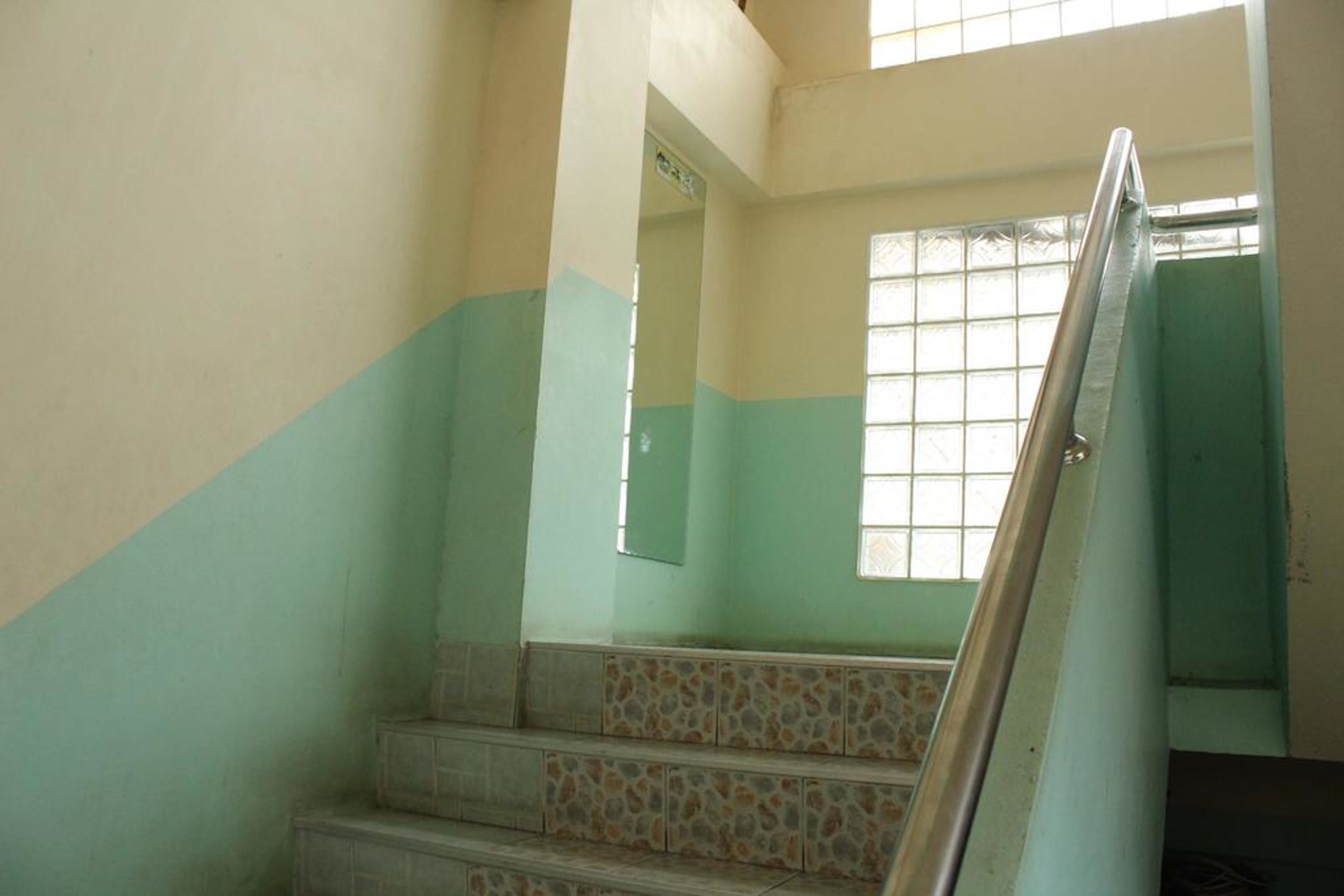 A staircase with a metal handrail, leading to a landing with a window.