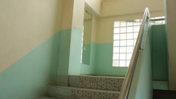 A staircase with a metal handrail, leading to a landing with a window.