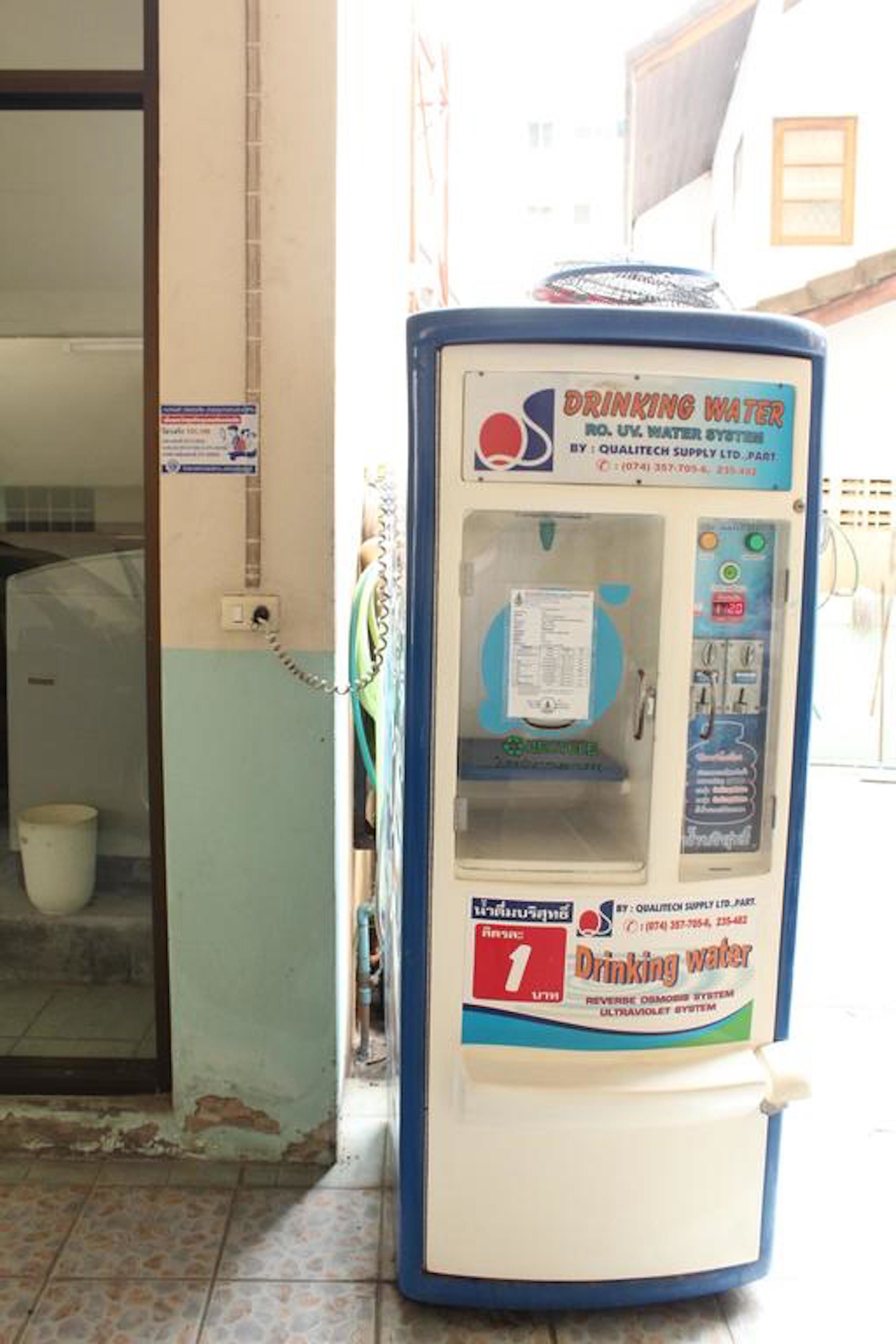 A drinking water dispenser with a manual pump, located near a door with a tiled floor.
