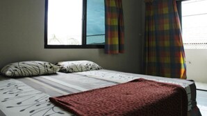 Un dormitorio con una cama, dos almohadas, una ventana con cortinas y un equipo de aire acondicionado.