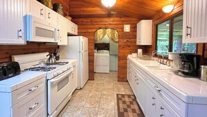 Une cuisine de taille réduite, avec des meubles blancs, une cuisinière, un four à micro-ondes et un réfrigérateur.