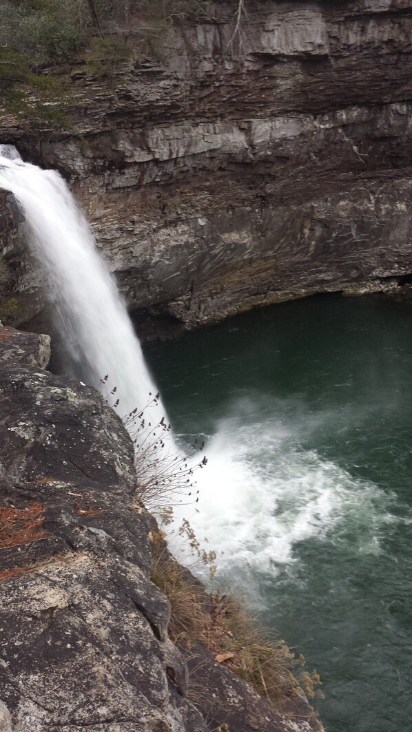 Une cascade se jetant dans un bassin, le tout entouré de falaises rocheuses.