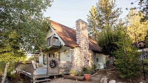 A house with a stone chimney, a wooden deck, and a gravel driveway. - Villa Pine Mountain- country cottage get away (green) Central AC  (Pine Mountain Club)