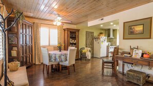 A dining area with a wooden table, chairs, and a ceiling fan. There is a kitchen in the background with a refrigerator and cabinets. - Villa Pine Mountain- country cottage get away (green) Central AC  (Pine Mountain Club)