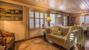 A cozy living room with a sofa, a chair, a lamp, and a painting on the wall. - Villa Pine Mountain- country cottage get away (green) Central AC  (Pine Mountain Club)