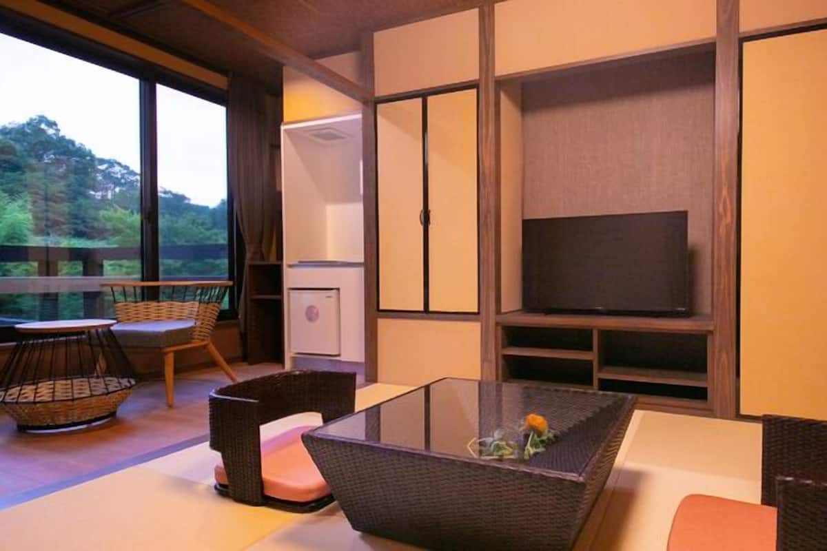 A room with a glass table, wicker furniture, a television, and sliding doors.