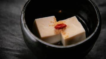 A black bowl containing a white cube with a red dot and a brown powder.