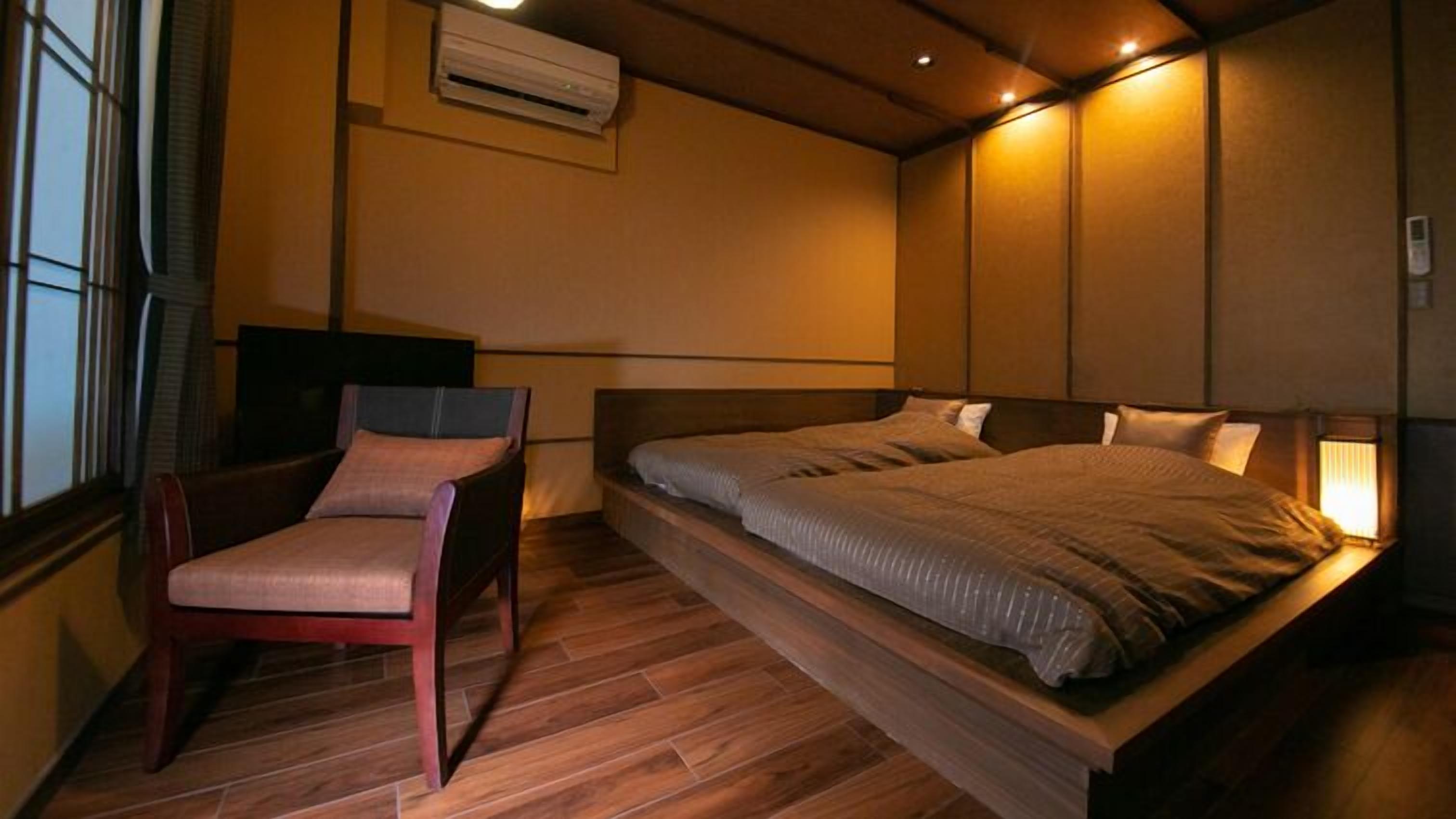 A bedroom with a bed, a chair, a TV, and a window.
