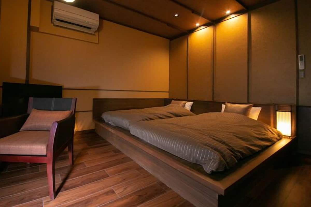 A bedroom with a bed, a chair, a TV, and a window.