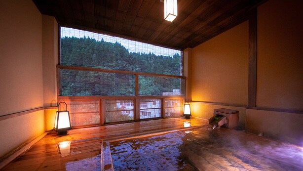 A wooden interior with a large window, two wall-mounted lanterns, and a wooden floor. - Hosenji Kanko Hotel Yumotoya (Kokonoe)