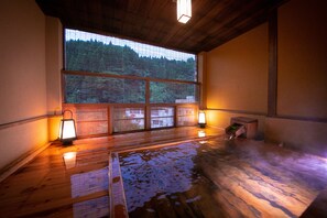 A wooden interior with a large window, two wall-mounted lanterns, and a wooden floor. - Hosenji Kanko Hotel Yumotoya (Kokonoe)