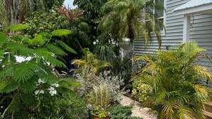 Um jardim bem cuidado com diversas plantas e um caminho que leva a uma casa.
