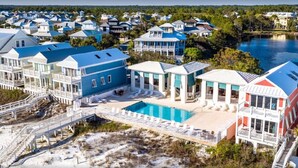 A coastal resort with multiple buildings, a swimming pool, and a bridge leading to the beach.