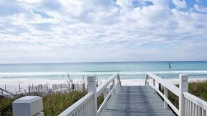 A wooden boardwalk leading to a beach with a clear view of the ocean.