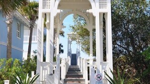 A white arched walkway leading to a building with a sign indicating 'Walk Over #1'.