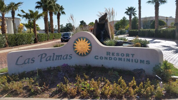 A sign for Las Palmas Resort Condominiums with a sun emblem, surrounded by palm trees and a paved area. - Comfortable condo close to mountain biking, swimming pools, national parks (St. George)