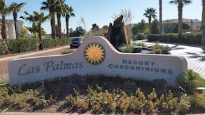 A sign for Las Palmas Resort Condominiums with a sun emblem, surrounded by palm trees and a paved area. - Comfortable condo close to mountain biking, swimming pools, national parks (St. George)