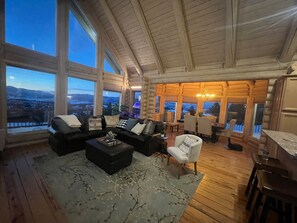 A spacious living room with a large window offering a scenic view, a cozy seating area, and a dining space.