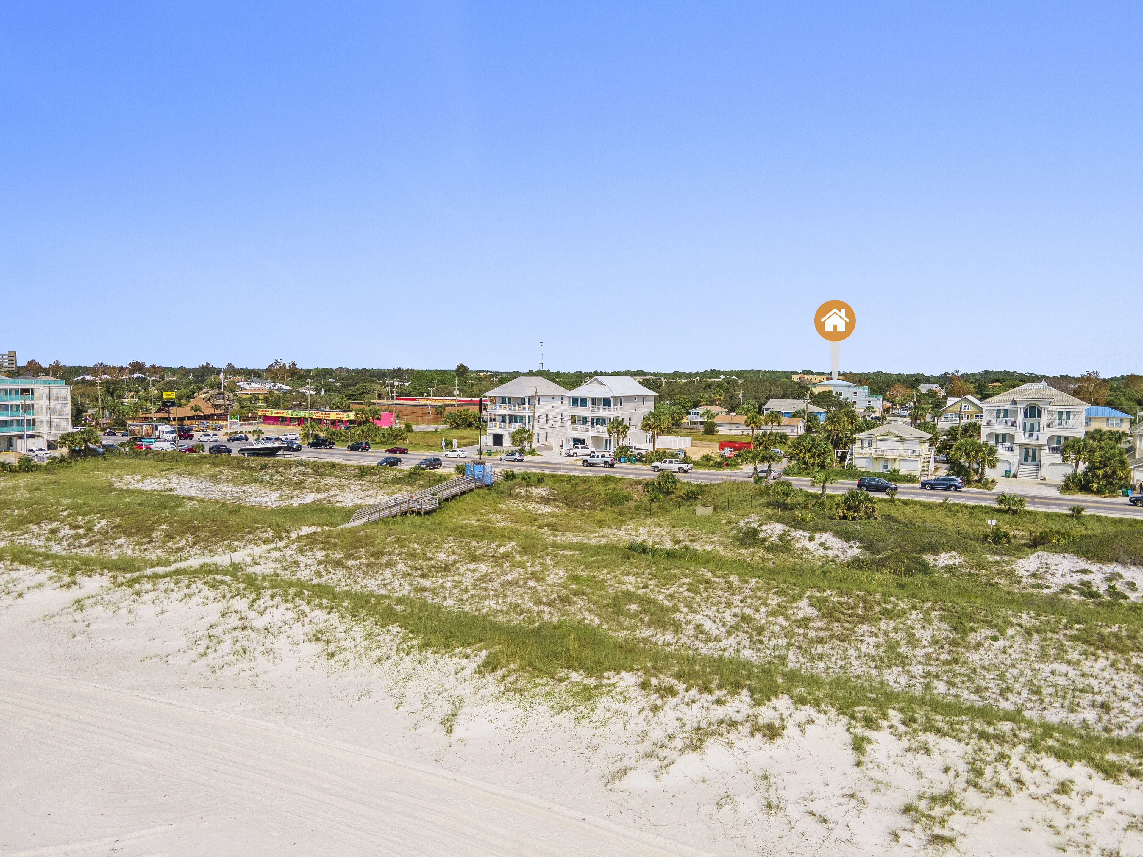 A coastal town with a beach in the foreground, buildings with balconies, and a clear sky.