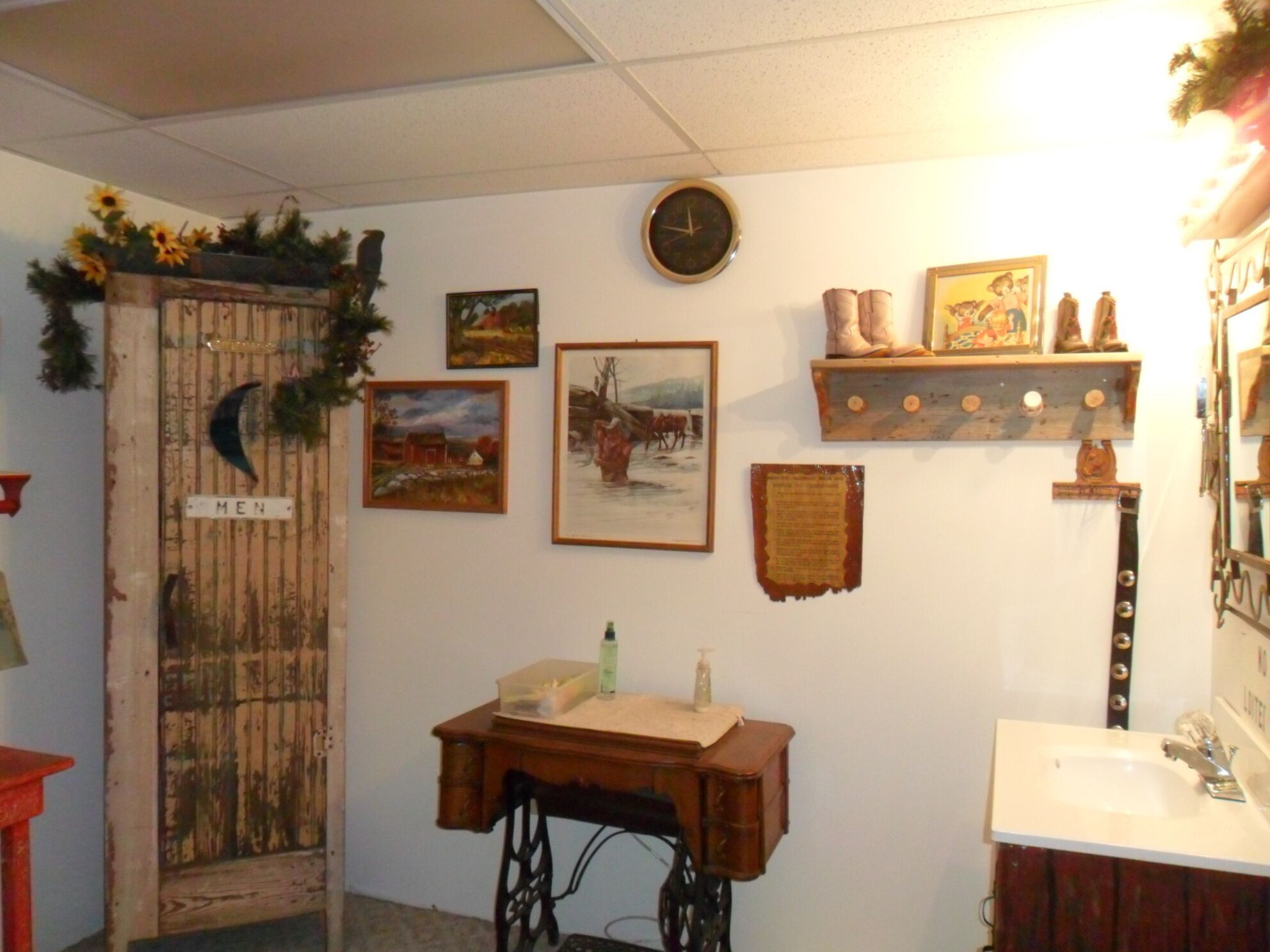Un baño rústico con puerta de madera, una máquina de coser antigua, un reloj y diversas decoraciones en la pared.