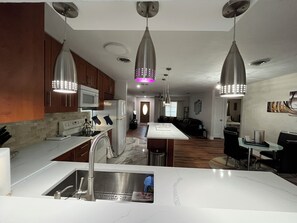 Una cocina moderna con electrodomésticos de acero inoxidable, iluminación colgante y encimera de mármol.