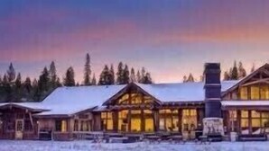 Un gran refugio con varias cabañas de madera, una chimenea destacada y un paisaje nevado.
