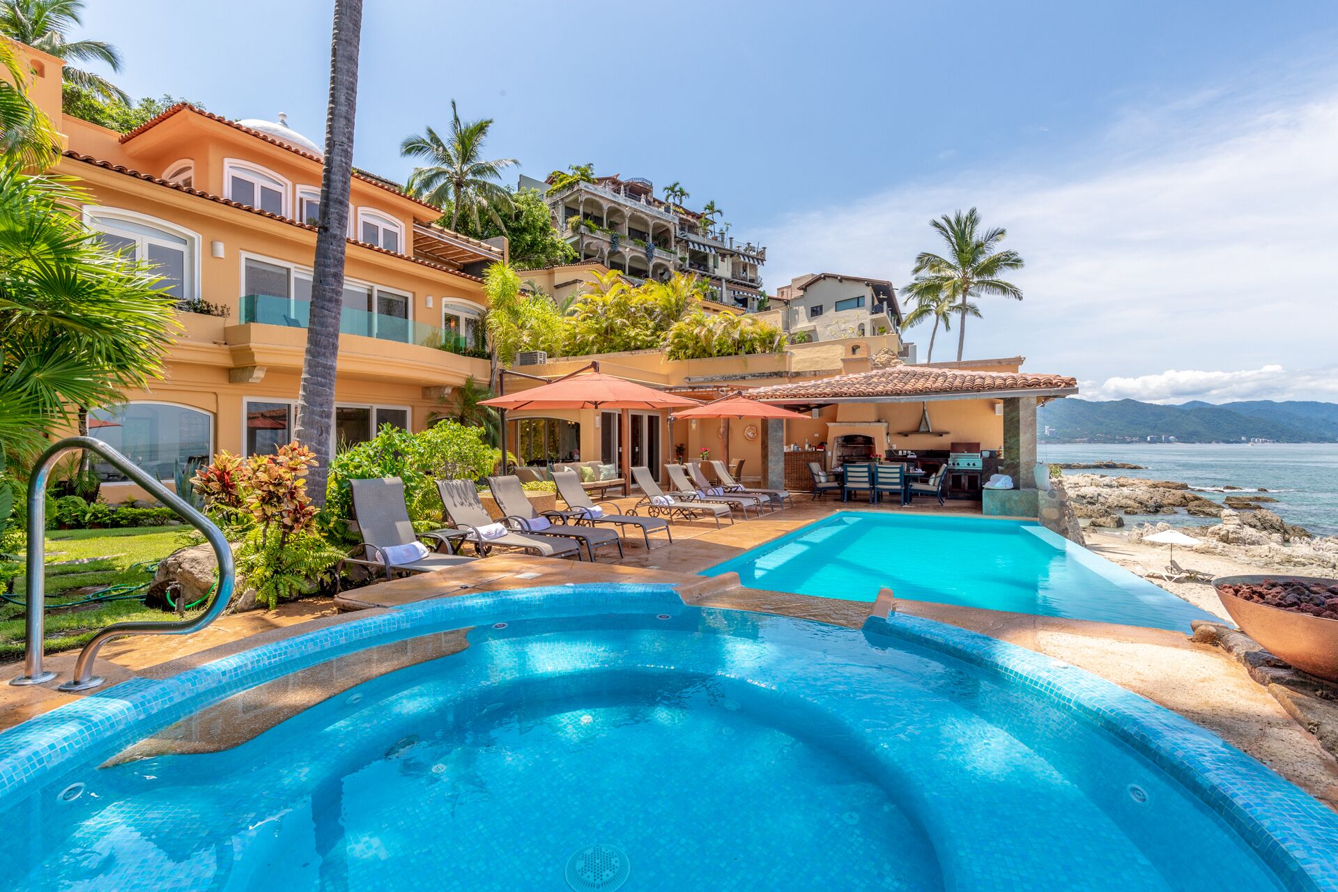 Un complexe hôtelier doté d’une piscine, de chaises longues et offrant une vue sur la mer.