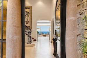 A hallway leading to a balcony with a view of the sea.