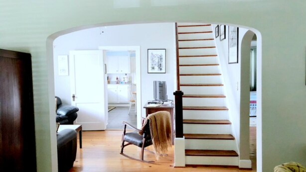 A spacious living room with a wooden staircase leading to another room. - Experience old Oriental (Oriental)