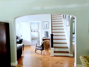 Un salon spacieux avec un escalier en bois menant à une autre pièce.
