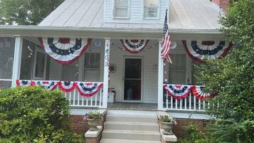 A two-story house with a porch decorated with American flags and patriotic bunting.