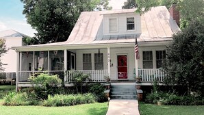 A two-story house with a front porch, a red door, and an American flag. - Experience old Oriental (Oriental)