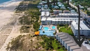 A coastal hotel with multiple buildings, a swimming pool, and a beach in the background. - Oceanfront Oasis (Tybee Island)