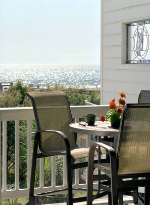 Ein Balkon mit zwei Stühlen, einem Tisch und einer Blumenvase.