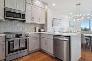 A modern kitchen with stainless steel appliances, white cabinetry, and a large island with seating.