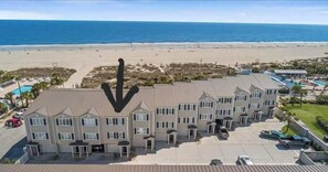 A beachfront hotel with multiple buildings, a swimming pool, and a parking area.