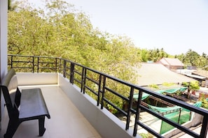 Ein Balkon mit einer Bank, umgeben von Bäumen und Gebäuden.