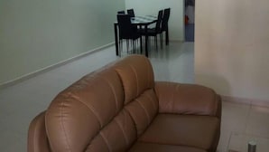 Un saló amb un sofà de cuir marró, una taula de dinar amb cadires i un ventilador de sostre.