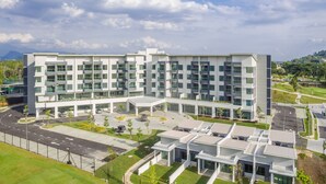 Un hôtel moderne à plusieurs étages, doté d’une cour intérieure, de nombreux balcons et d’un espace de stationnement.