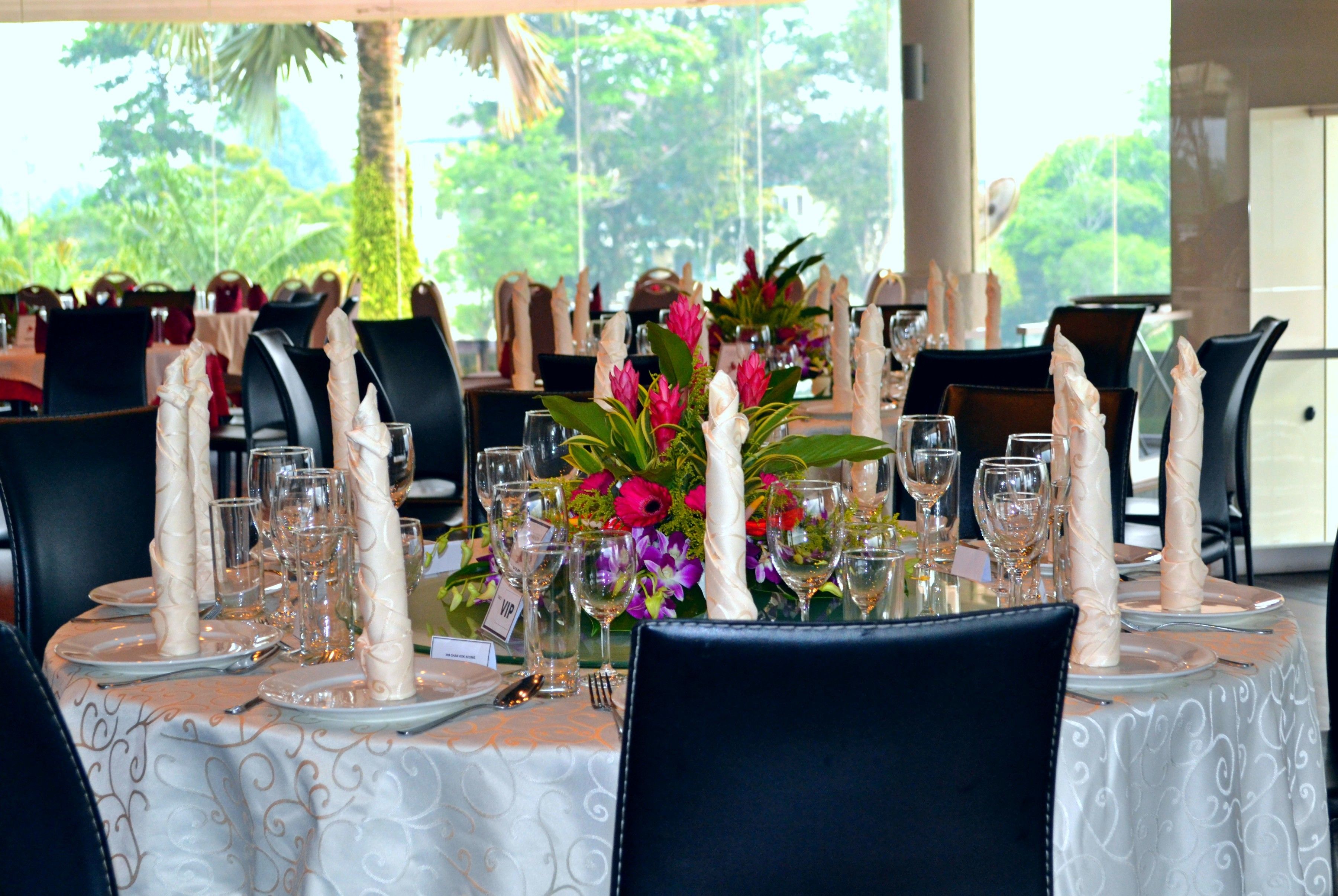 A table set for a formal dining event with a view of lush greenery.