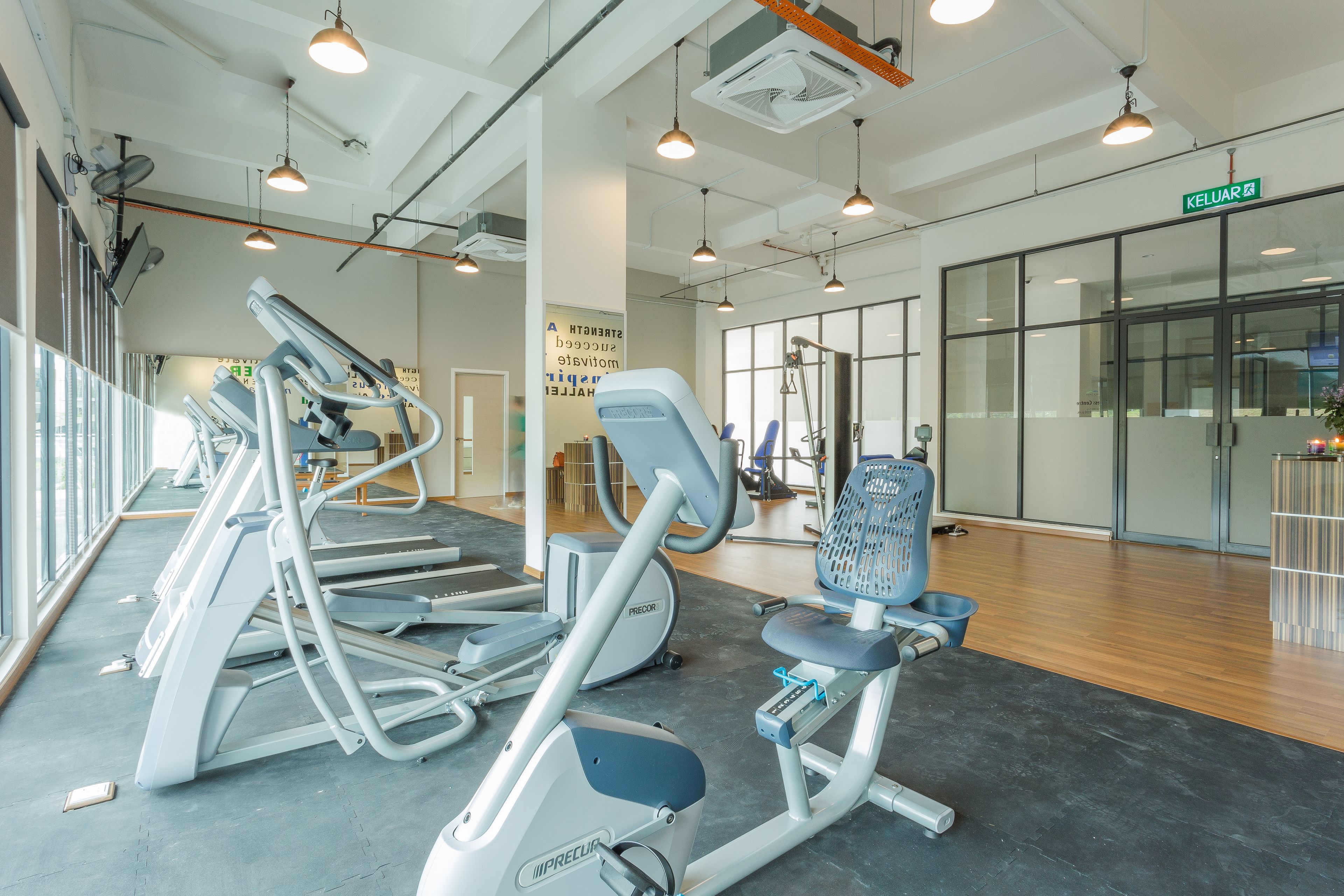 Un gimnasio con cintas de correr, elípticas y una máquina de remo.