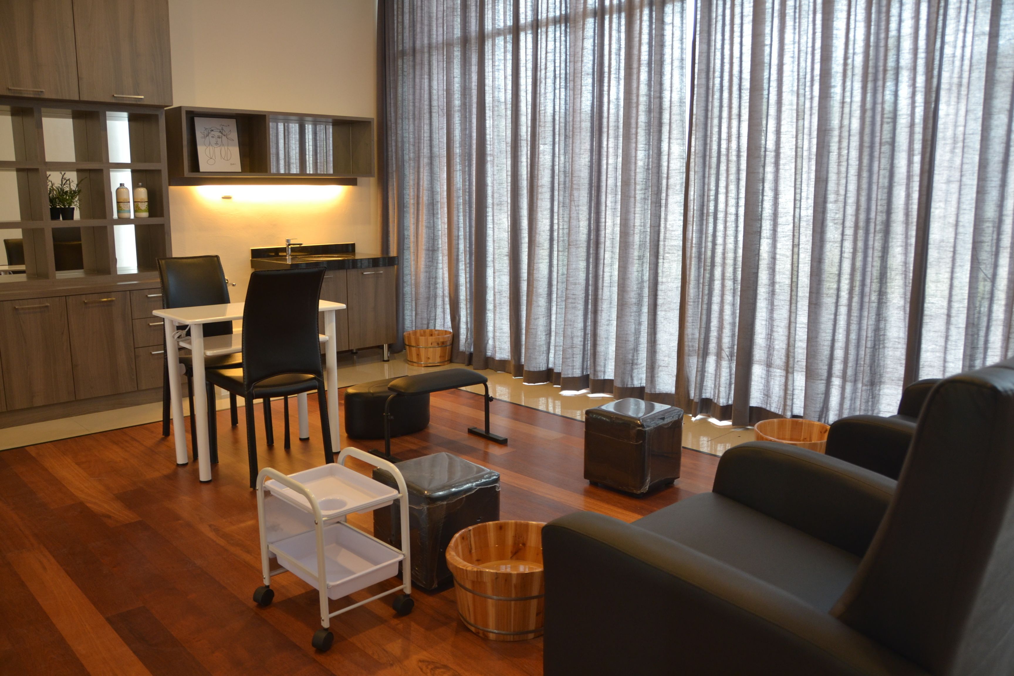 A modern living room with a sofa, a dining table with chairs, a kitchen area with cabinets, and a large window with curtains.