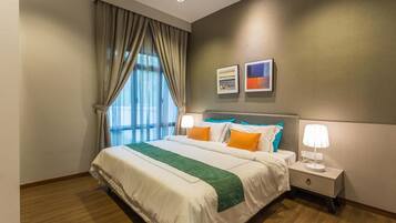 Habitación de hotel con una cama grande, dos mesitas de noche con lámparas, una ventana con cortinas y dos cuadros en la pared.