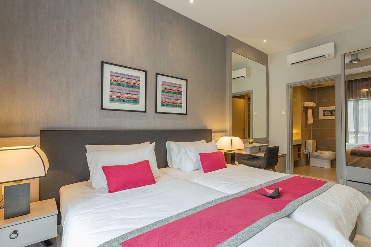 Une chambre d’hôtel avec un grand lit, des tables de chevet, un bureau et une salle de bain visible à travers une porte ouverte.