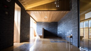 Ein modernes Interieur mit Holzboden, Steinwänden und einer Glastür, die nach draußen führt.