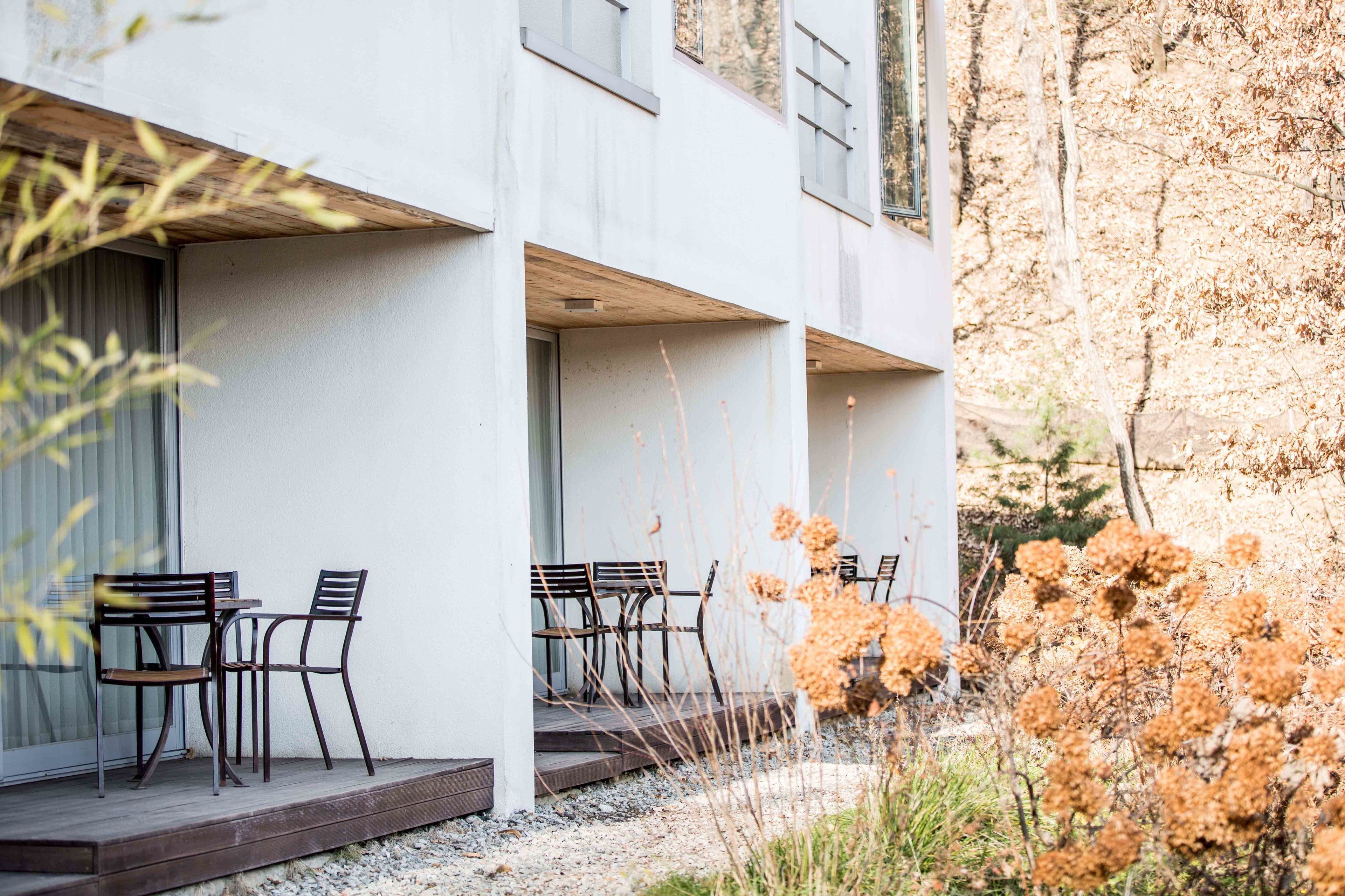 A modern building with a covered outdoor seating area featuring tables and chairs.