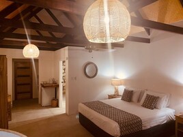 A bedroom with a large bed, a bedside table, a lamp, and a hanging light fixture.