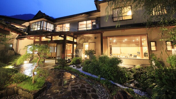 Un bâtiment de style japonais traditionnel, doté d'un bassin à carpes koï, d'un sentier de pierres et d'une végétation luxuriante.