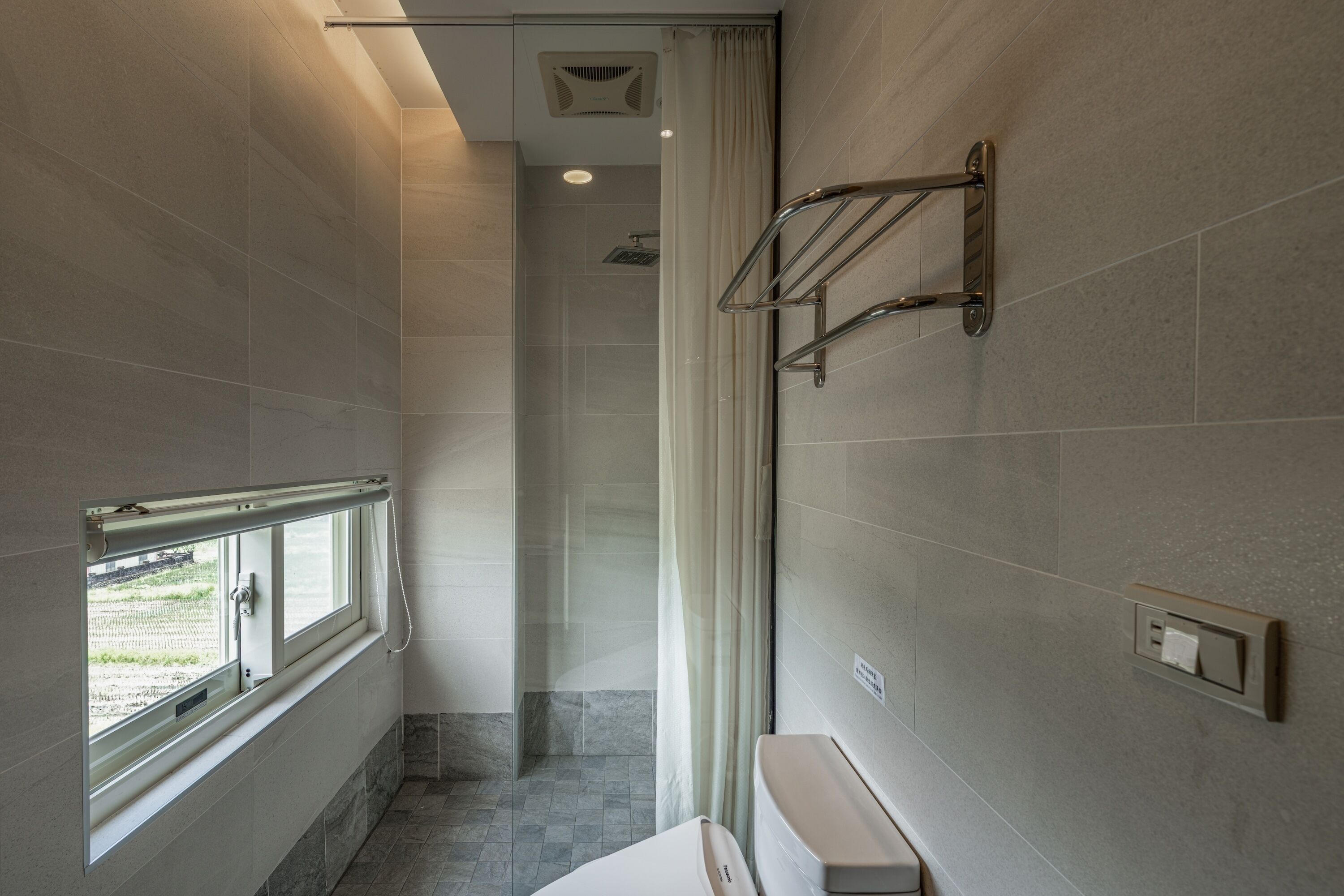 Un baño moderno con ducha, inodoro y ventana.