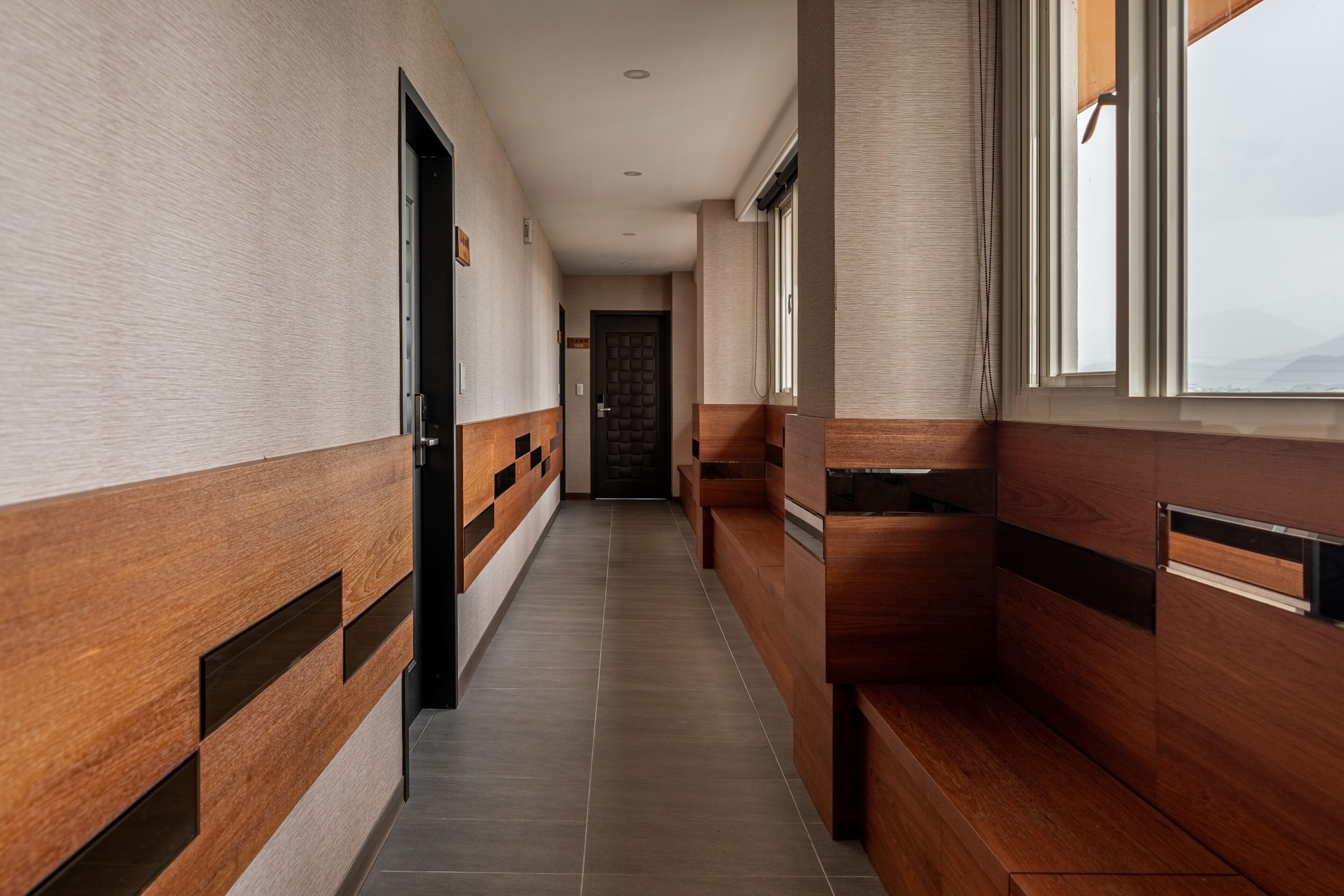 A hallway with wooden paneling and a tiled floor, leading to a door at the end.
